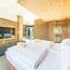 Modernes Schlafzimmer mit Holzdecke, großem TV und weißen Bettdecken